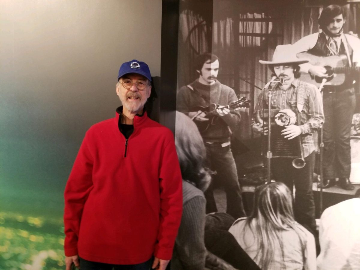 Les Thompson at the Country Music Hall of Fame standing next to a mural of himself and other Nitty Gritty Dirt Band members. Photo provided by Les Thompson.